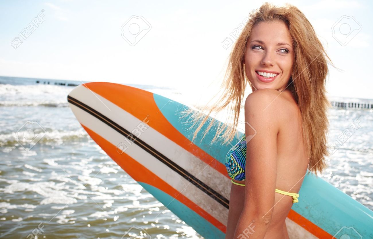 21338849-Beautiful-Young-Woman-Surfer-Girl-in-Bikini-with-Surfboard-at-a-Beach--Stock-Photo