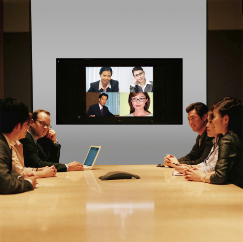 Businesspeople seated around conference table and monitor